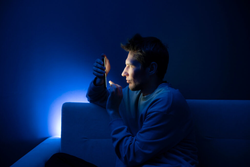 Man squinting at his phone in the dark