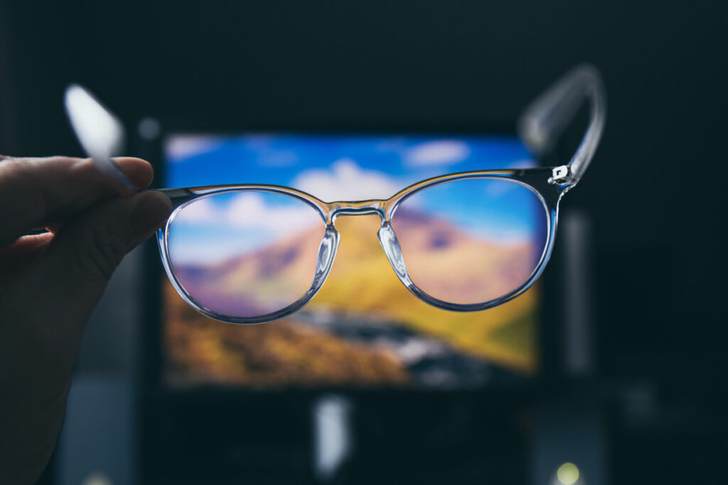 Hand holding blue light glasses and screen