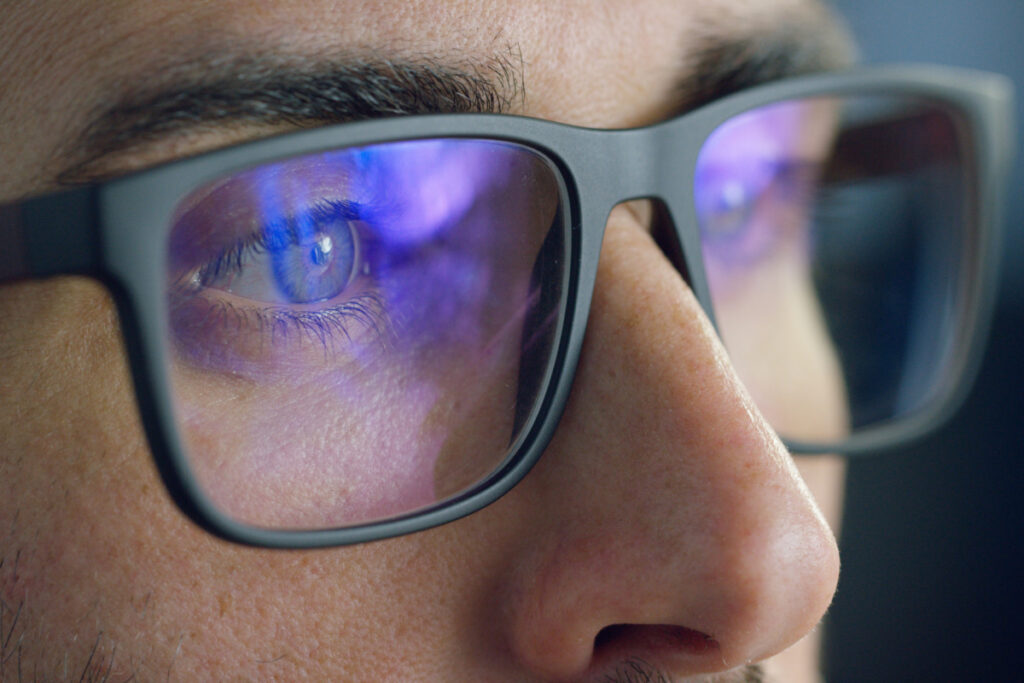 Close up of man with blue light blocking glasses staring at a screen