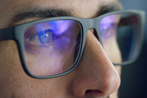 Close up of man with blue light blocking glasses staring at a screen